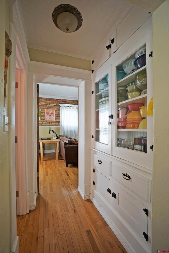 hallway with ornamental molding and light wood-type flooring