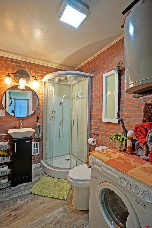 bathroom with an enclosed shower, wood-type flooring, brick wall, and washer / dryer