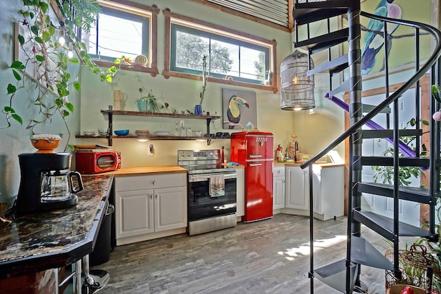 kitchen with wood-type flooring, electric range, and white cabinetry