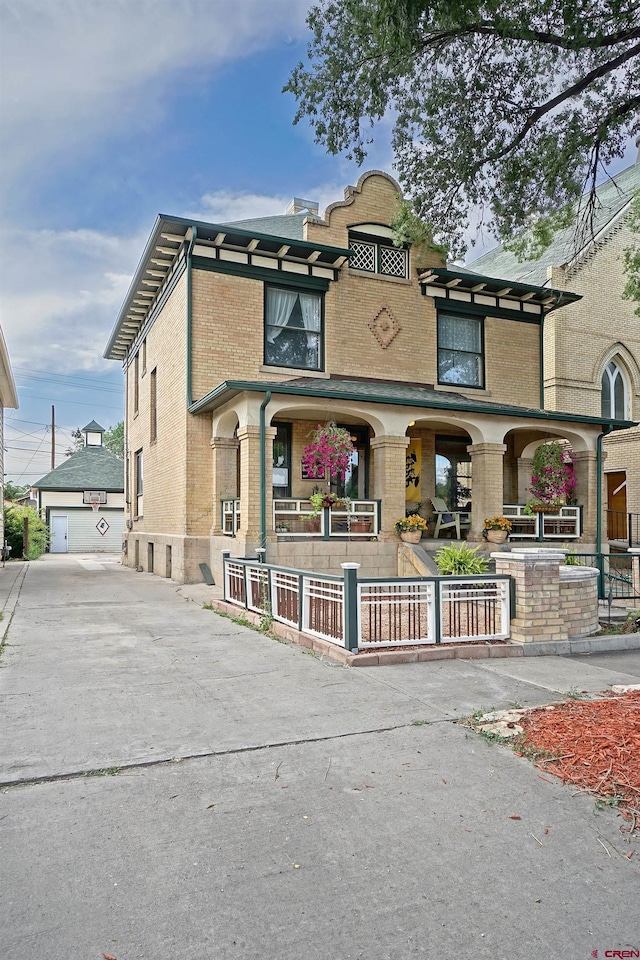 view of front of home featuring a garage, an outdoor structure, and covered porch