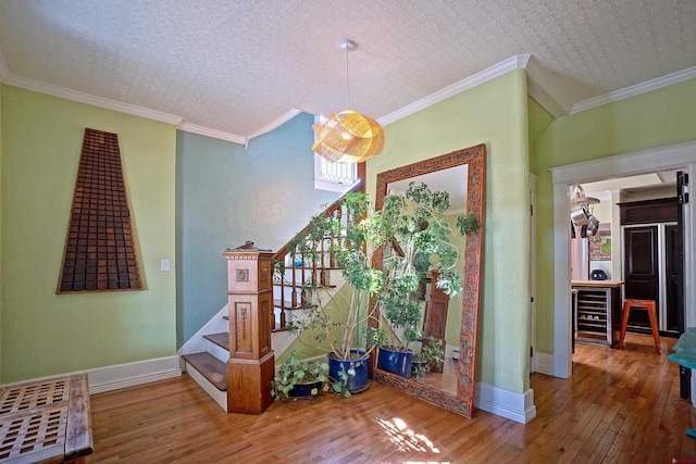 stairs with beverage cooler, ornamental molding, and hardwood / wood-style flooring