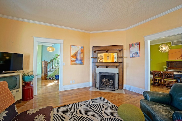 living room featuring a textured ceiling, light hardwood / wood-style flooring, crown molding, and a chandelier