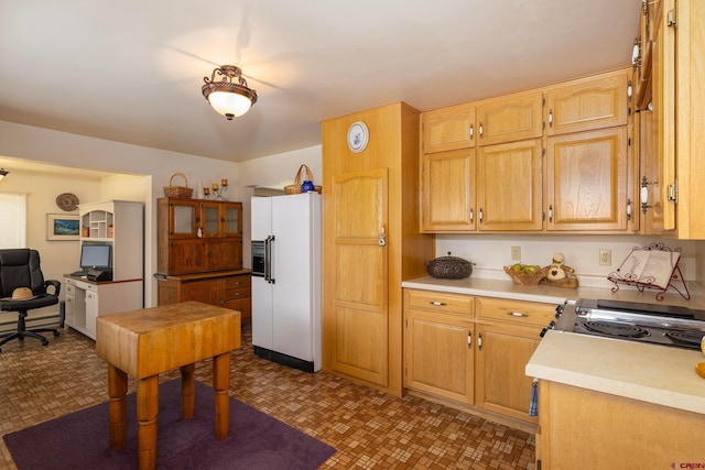 kitchen with range, light brown cabinetry, tile patterned floors, and white fridge with ice dispenser