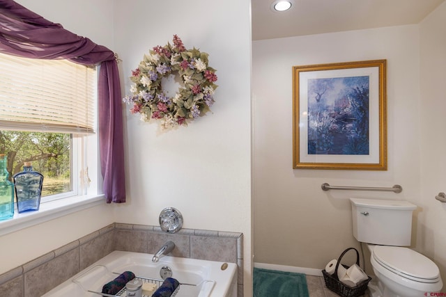 bathroom with a tub to relax in and toilet