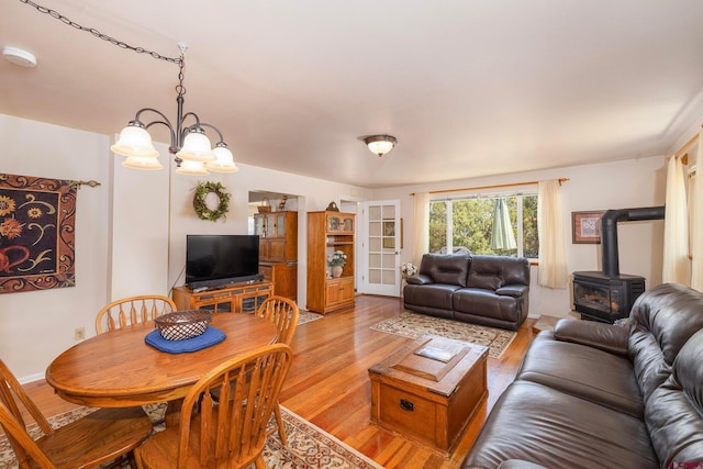 dining space featuring a wood stove, light hardwood / wood-style floors, and a chandelier