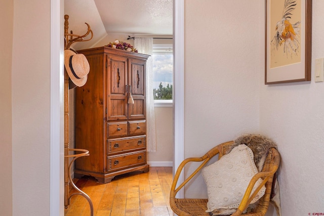 sitting room featuring light wood-type flooring, vaulted ceiling, and a textured ceiling