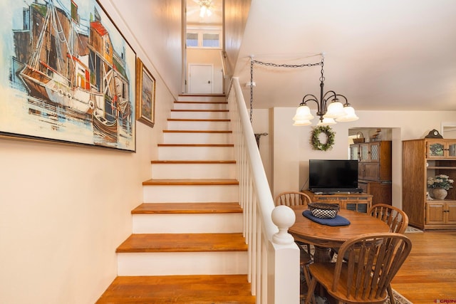 staircase featuring an inviting chandelier and light hardwood / wood-style flooring