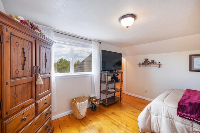 bedroom with a textured ceiling and light hardwood / wood-style floors