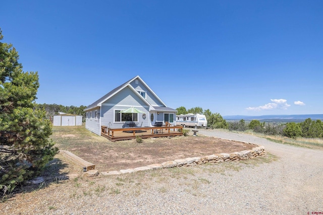 view of front of property with a deck and a storage shed