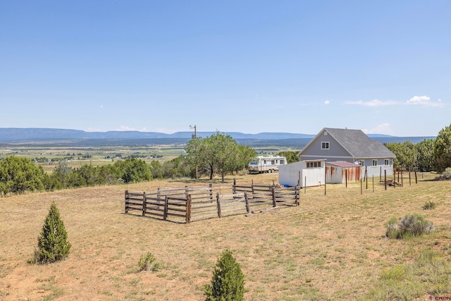 view of yard featuring a mountain view, an outdoor structure, and a rural view