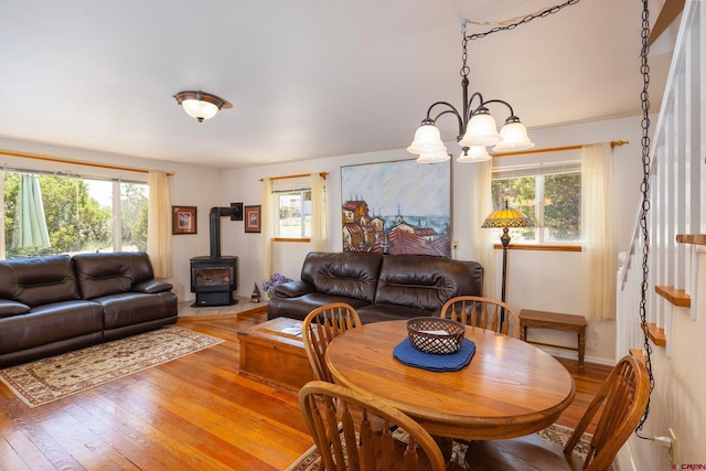 dining area featuring a notable chandelier, a wood stove, hardwood / wood-style flooring, and plenty of natural light