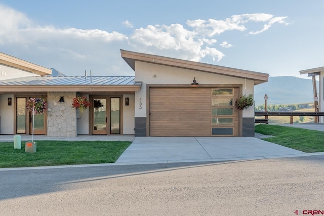 contemporary home with a garage, a mountain view, and a front lawn