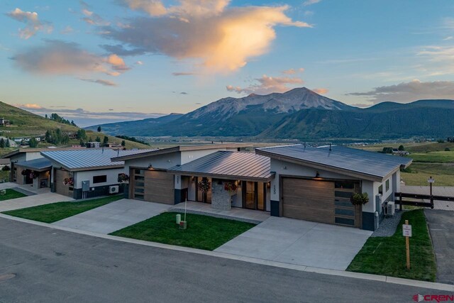 modern home featuring a garage, a mountain view, and a yard