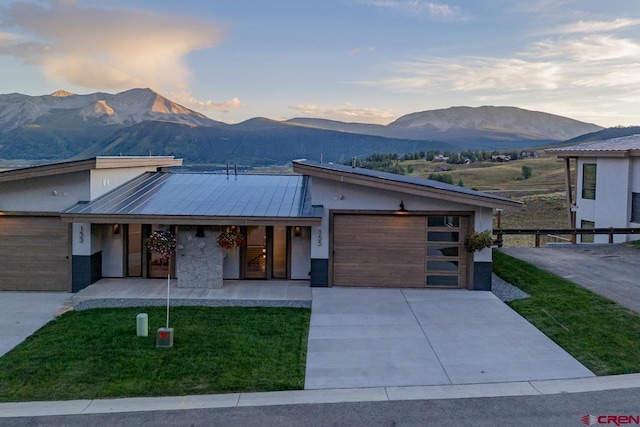 view of front of house featuring a garage, a mountain view, covered porch, and a lawn