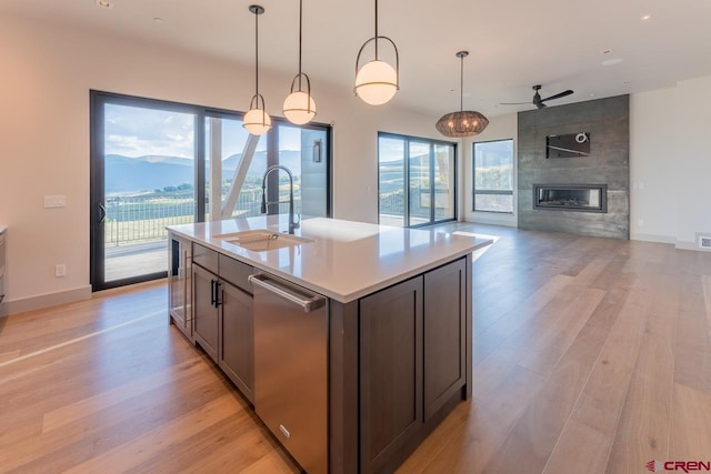 kitchen featuring sink, dishwasher, an island with sink, a mountain view, and decorative light fixtures