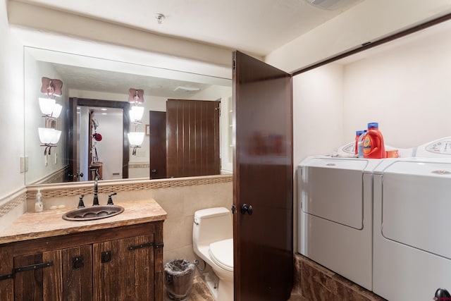 bathroom with vanity, tile walls, washer and dryer, and toilet