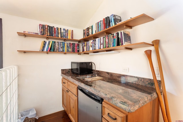 kitchen featuring dark stone counters, vaulted ceiling, sink, stainless steel dishwasher, and dark wood-type flooring