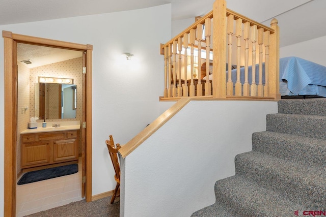 stairs with lofted ceiling, carpet, and sink