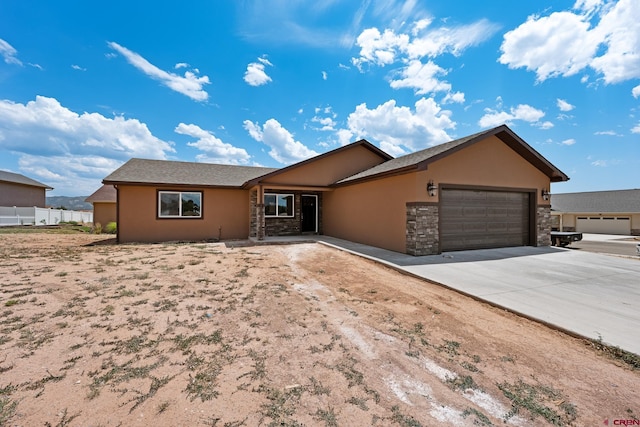 single story home featuring a garage, stone siding, driveway, and stucco siding