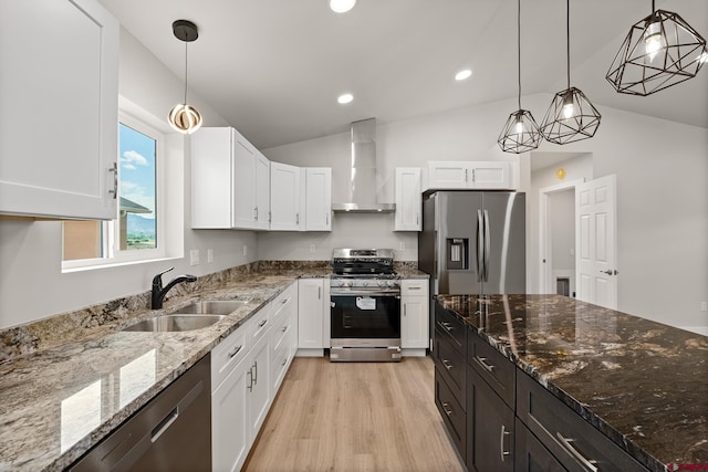 kitchen featuring hanging light fixtures, light hardwood / wood-style flooring, wall chimney range hood, and stainless steel appliances