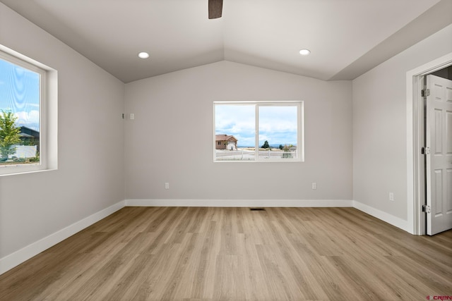 empty room with vaulted ceiling, a healthy amount of sunlight, and light wood-type flooring