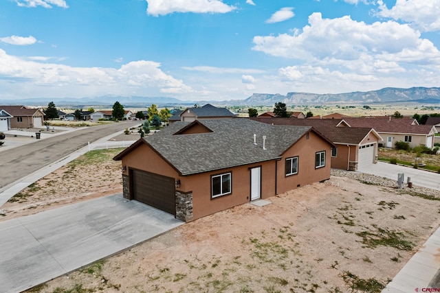 ranch-style home featuring a garage, a residential view, a mountain view, and stucco siding