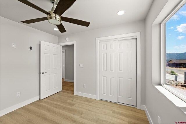 unfurnished bedroom featuring light wood-type flooring, ceiling fan, and a closet