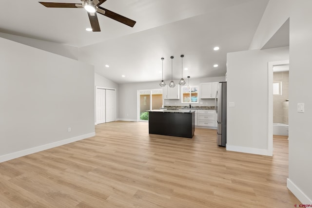 kitchen with a kitchen island, white cabinets, light countertops, freestanding refrigerator, and decorative light fixtures