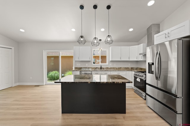 kitchen featuring appliances with stainless steel finishes, dark stone counters, white cabinetry, and a kitchen island