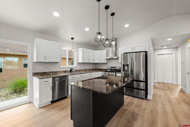 kitchen featuring white cabinetry, dark stone countertops, light hardwood / wood-style flooring, stainless steel appliances, and hanging light fixtures