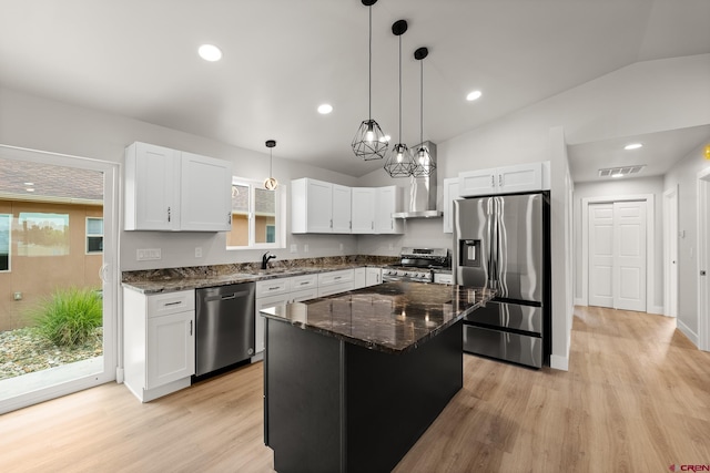 kitchen featuring white cabinetry, appliances with stainless steel finishes, a center island, dark stone countertops, and decorative light fixtures