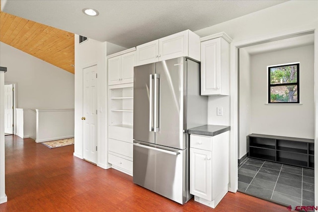 kitchen featuring white cabinetry, lofted ceiling, stainless steel fridge, and wood ceiling