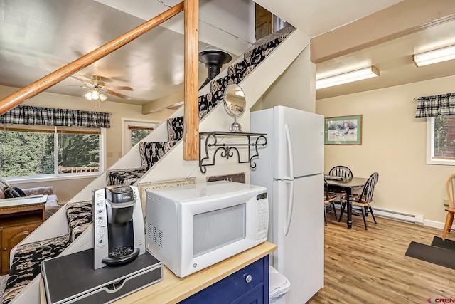 kitchen with white appliances, a baseboard heating unit, ceiling fan, light hardwood / wood-style floors, and blue cabinetry