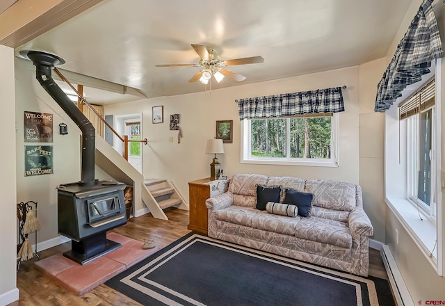 living room featuring a baseboard radiator, a wood stove, ceiling fan, and hardwood / wood-style floors