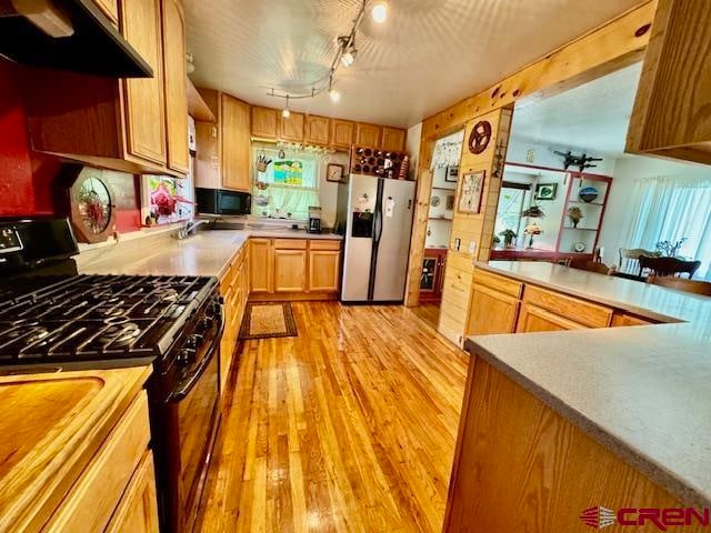 kitchen with track lighting, black appliances, extractor fan, and light wood-type flooring