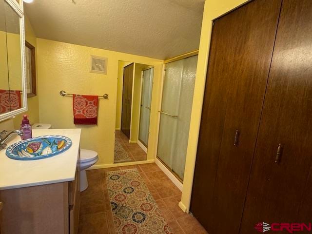 bathroom with an enclosed shower, a textured ceiling, tile patterned floors, toilet, and vanity