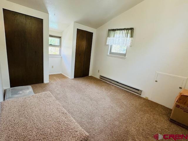 unfurnished bedroom featuring light colored carpet, a closet, lofted ceiling, and a baseboard heating unit