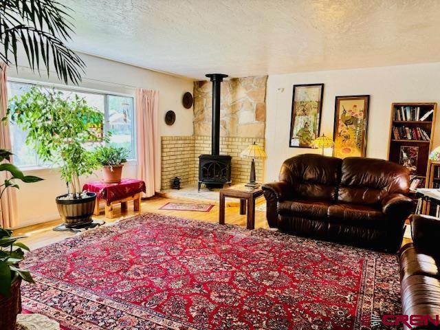 living room featuring a textured ceiling, a wood stove, and wood-type flooring