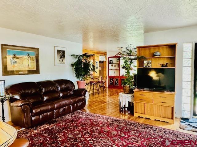 living room featuring light wood-type flooring and a textured ceiling