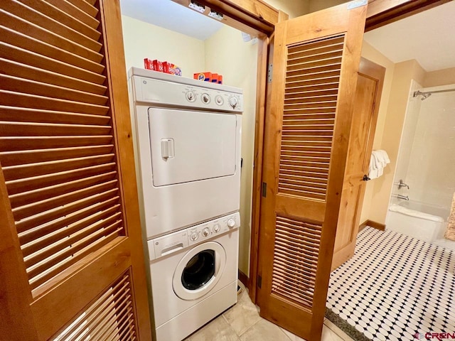 clothes washing area featuring light tile patterned flooring and stacked washing maching and dryer