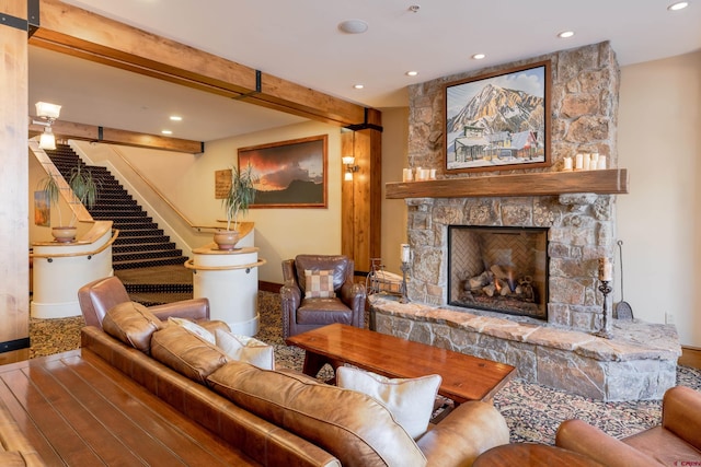 living room with wood-type flooring, beamed ceiling, a fireplace, and a barn door