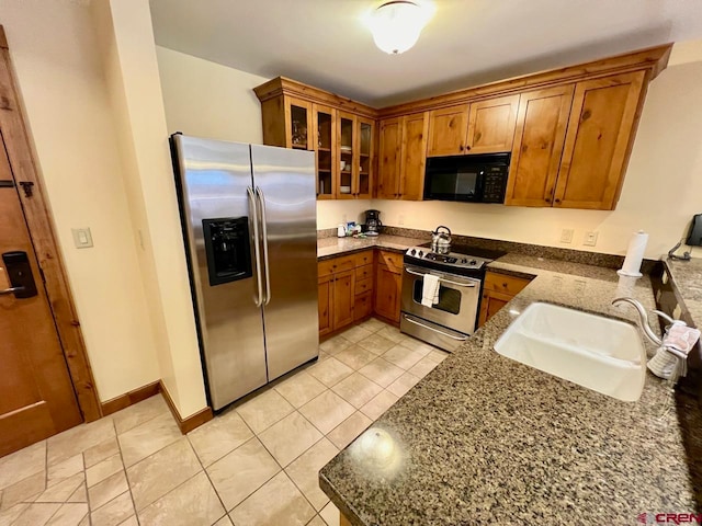 kitchen with light tile patterned flooring, appliances with stainless steel finishes, sink, and dark stone counters