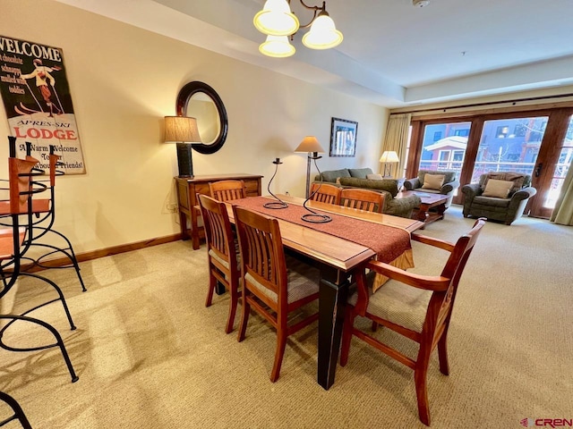 dining room featuring light carpet and a chandelier