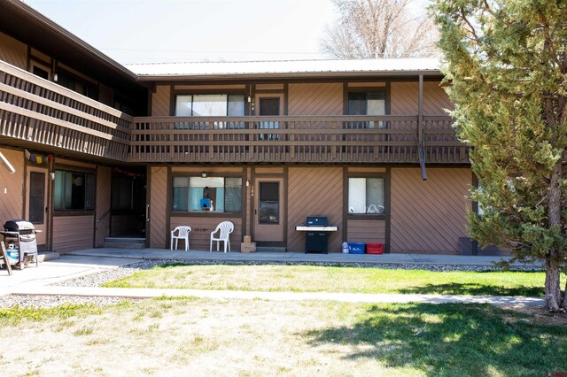 back of property with a balcony and a lawn