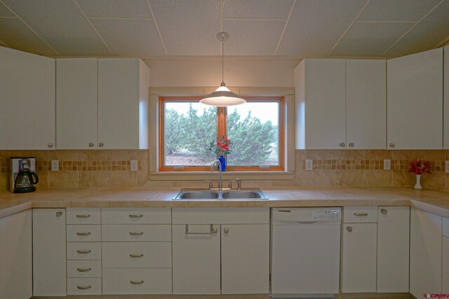 kitchen featuring sink, tasteful backsplash, white dishwasher, and white cabinetry