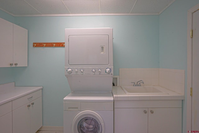 clothes washing area featuring sink, cabinets, and stacked washer / drying machine