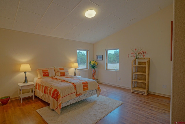 bedroom with wood-type flooring and vaulted ceiling