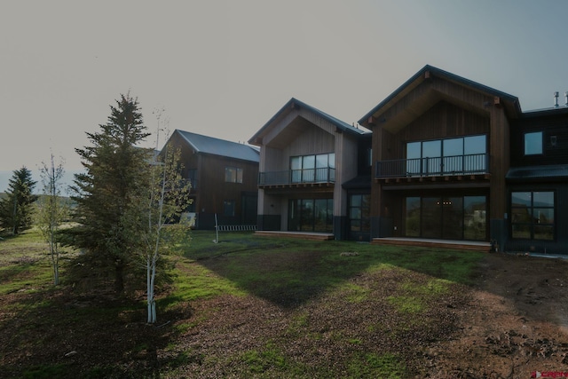 back of house featuring a balcony and a yard