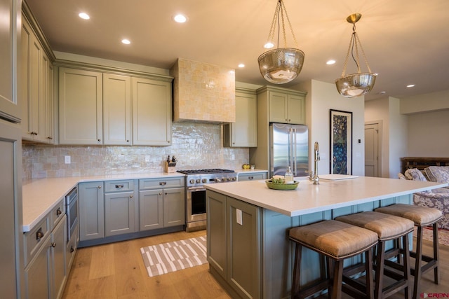 kitchen with wall chimney range hood, light hardwood / wood-style floors, a kitchen island, decorative backsplash, and premium appliances