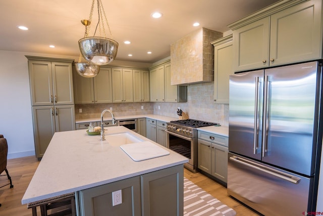 kitchen featuring tasteful backsplash, premium range hood, light hardwood / wood-style floors, hanging light fixtures, and high end appliances